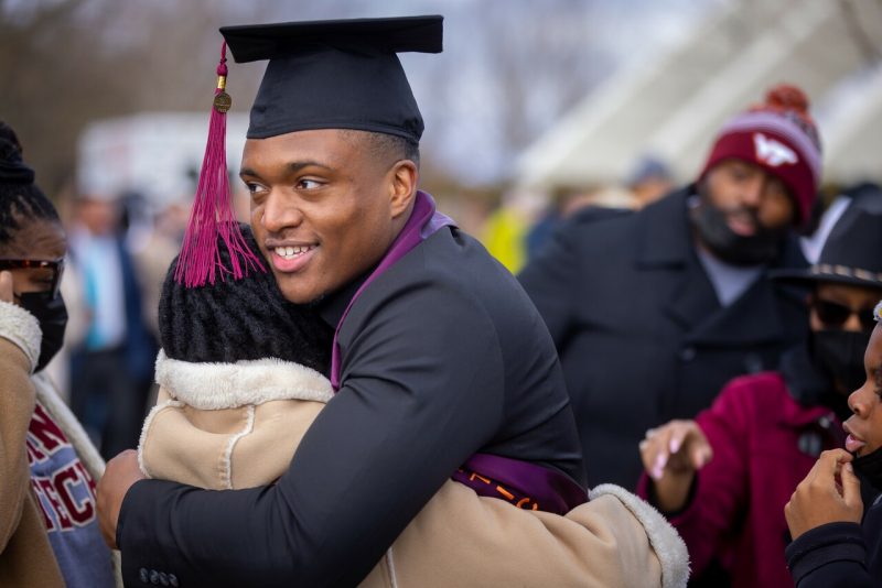 fall commencement at Virginia Tech. Graduate hugs family member.